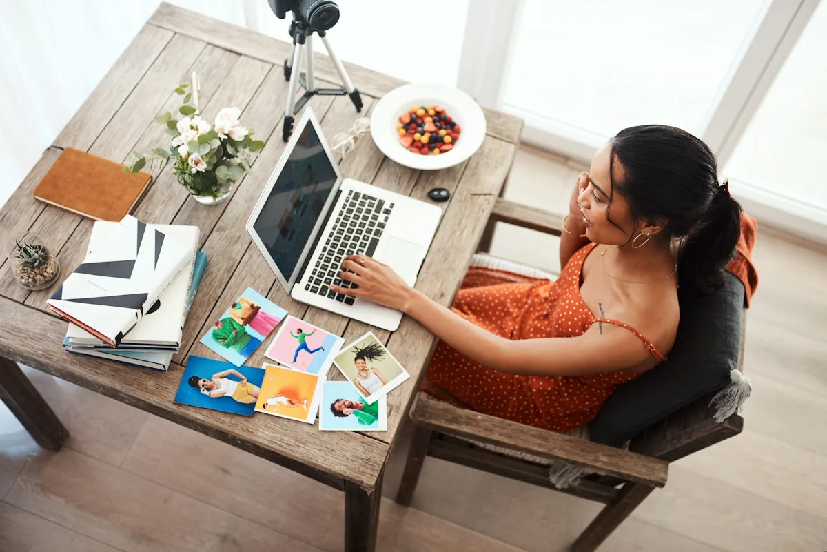 Une femme qui travaille sur un ordinateur posé sur la table à côté de quelques images