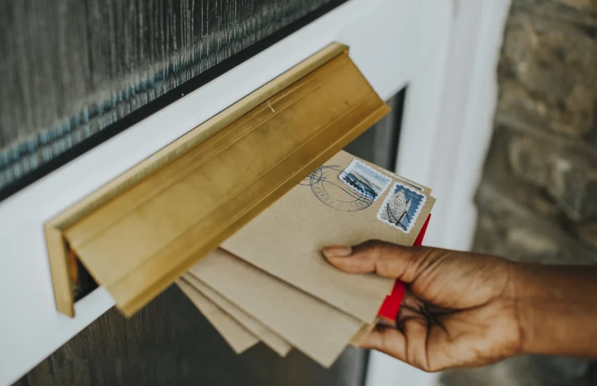 Une main qui prend des courriers dans une boîte aux lettres
